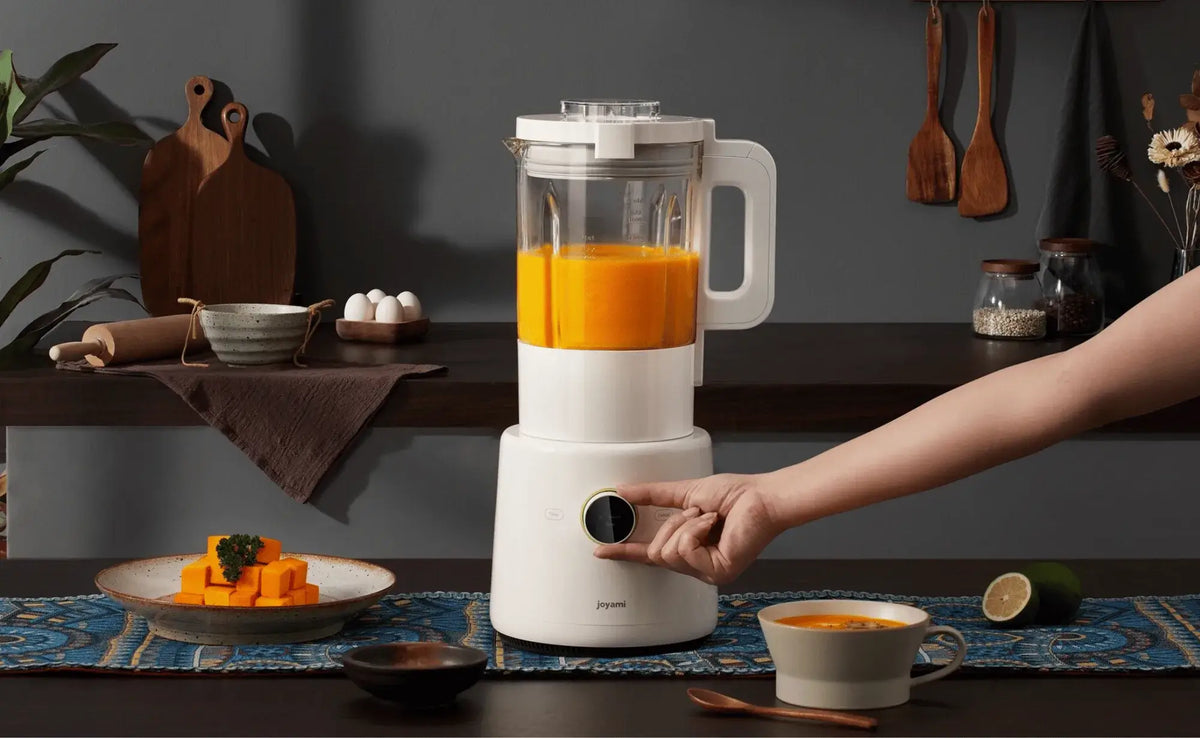 Persoon bedient een witte Xiaomi Joyami blender vol vers jus in een Aziatische keuken