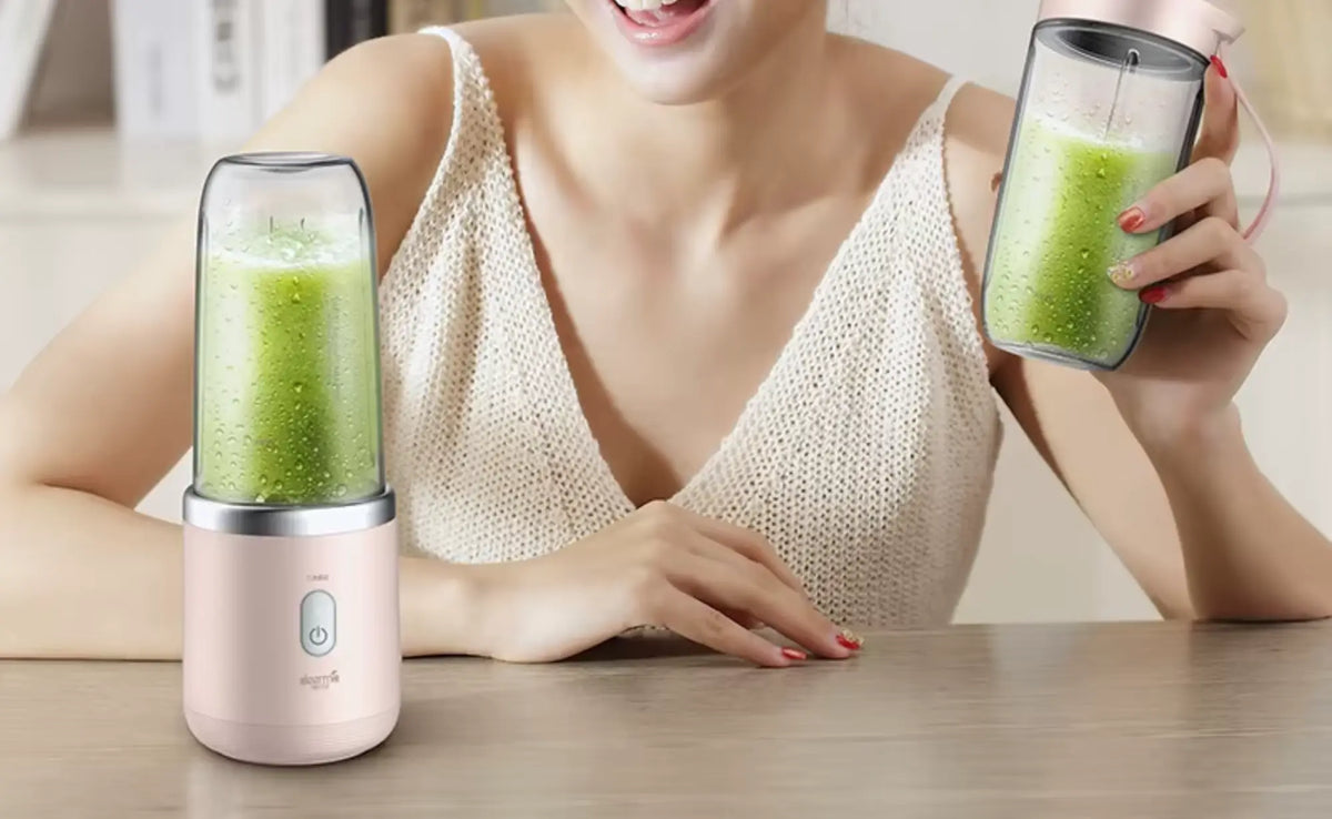 Vrouw met twee glazen groene smoothies uit Xiaomi personal blenders met draagbare drinkbekers