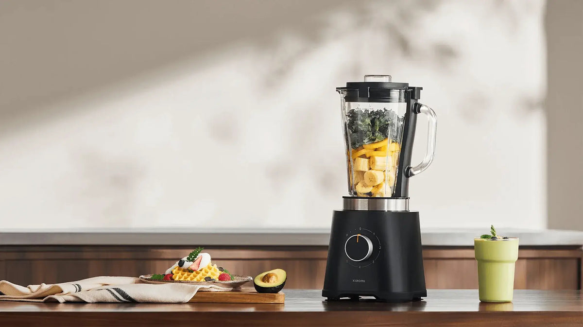 Zwarte Xiaomi blender met bananen, spinazie en ingrediënten omgeven door een groene smoothie en gerechten