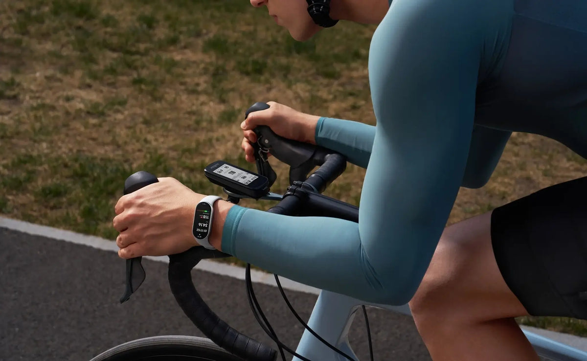 Persoon draagt Xiaomi Smart Band 10 fitnessband terwijl hij fietst met een bike computer