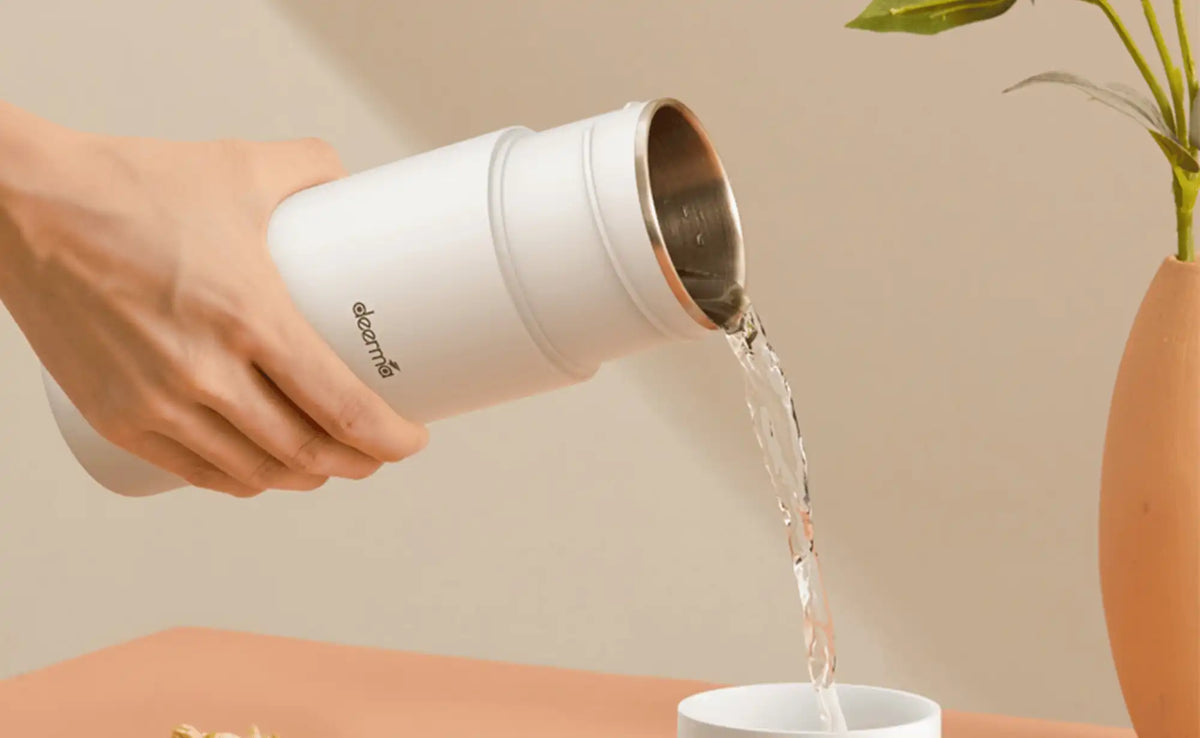 Close-up water stroomt uit een witte Xiaomi waterkoker in een kopje