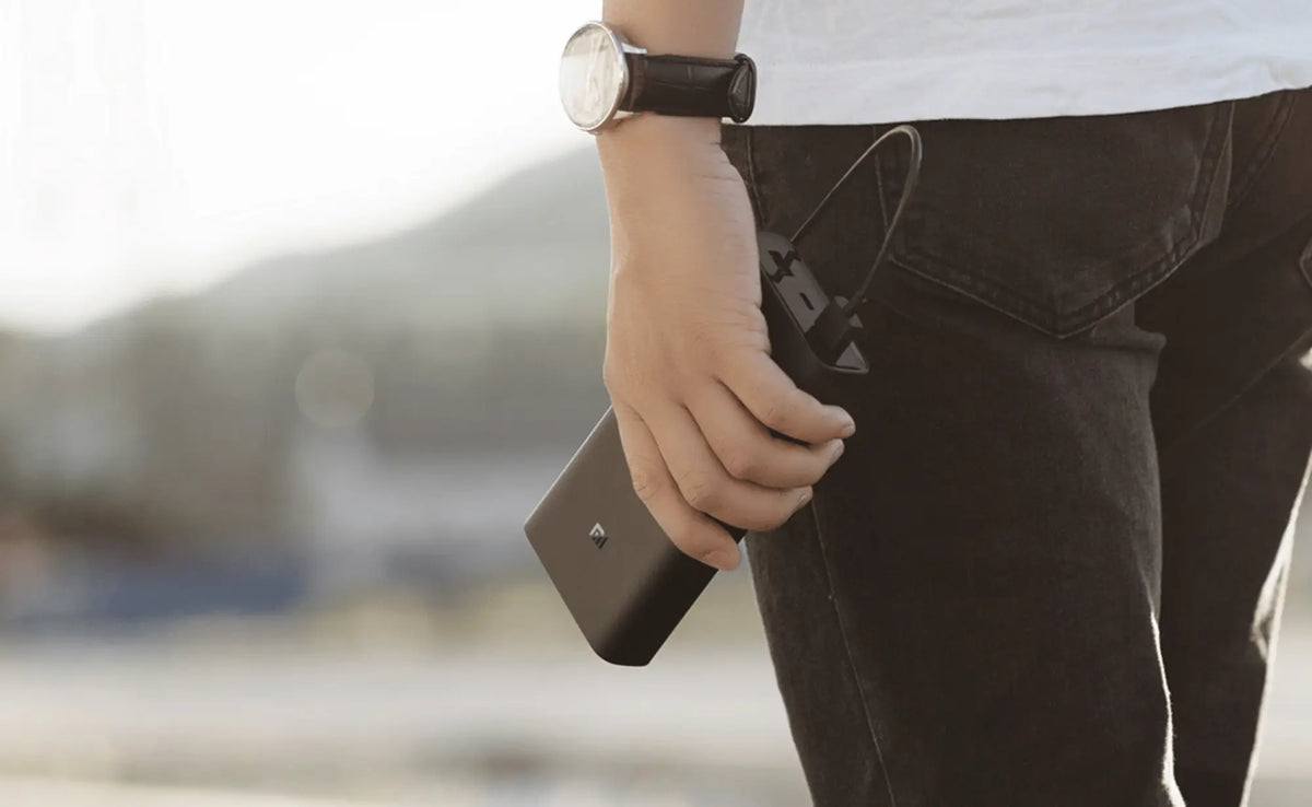 Persoon met een compacte Xiaomi powerbank in de hand bij een buitenactiviteit aan het water