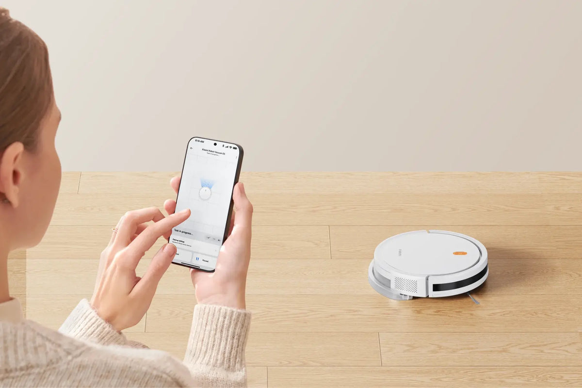 Vrouw bedient de Xiaomi Robot Vacuum E5 slimme stofzuiger via de app op haar telefoon
