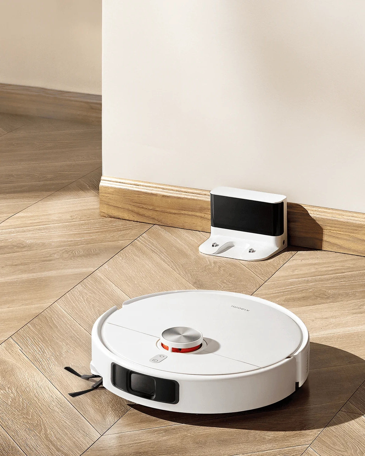 Witte Xiaomi robotstofzuiger rijdt naar het oplaadstation op een houten visgraatvloer